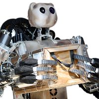 BEAR a two handed, three fingered robot, with a bear shaped head holds a wood crate to its torso.