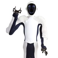 Close-up of EVE, a black and white soft humanoid robot. It's face displays blue circles for eyes, and a smile. One of it's two gripper hands is raised in a greeting.
